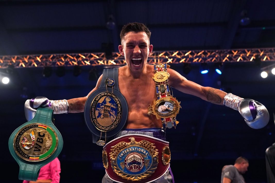 Liam Davies celebrating the boxing ring with four belts
