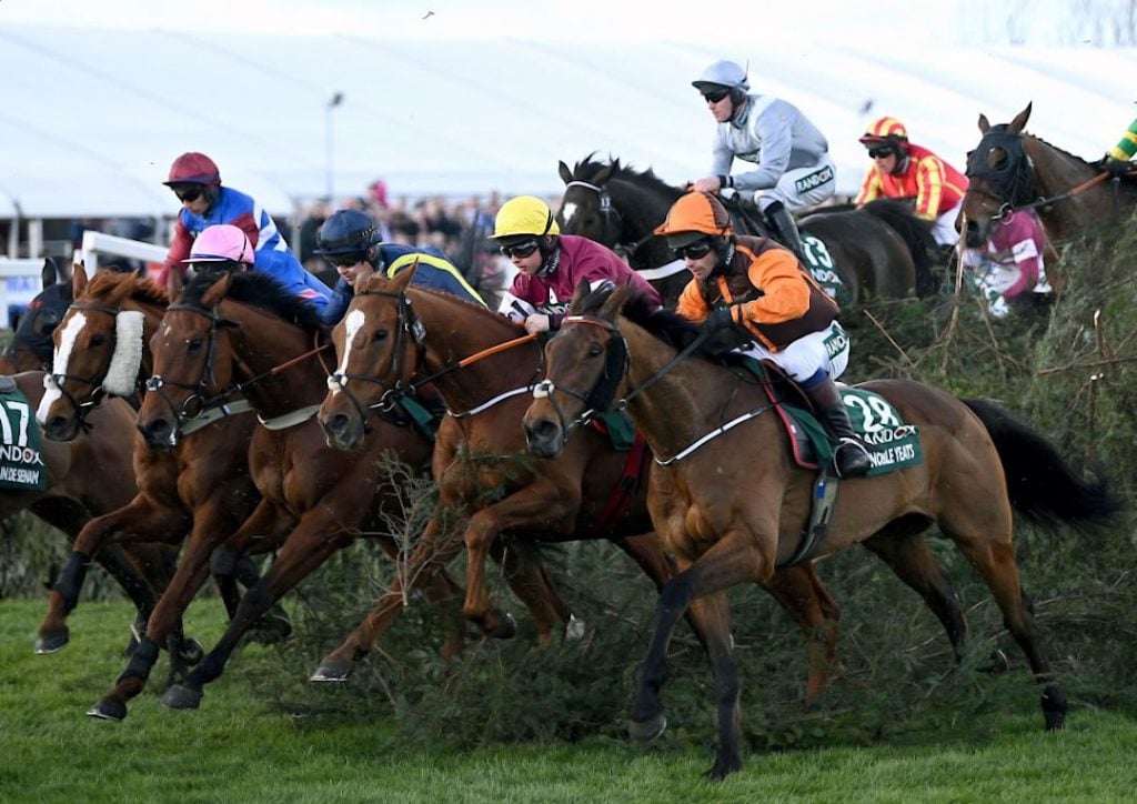 A photo of horses jumping over a fence