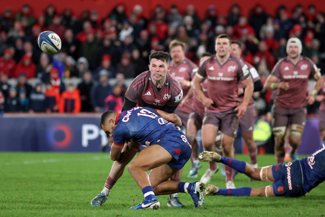 Munster Rugby player making a pass while being tackled